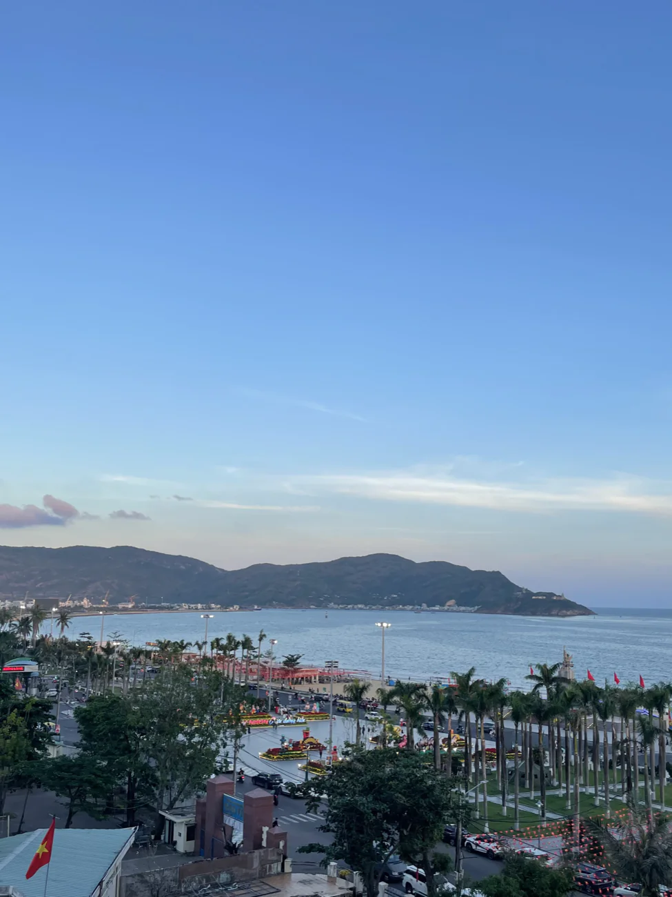 The wide blue bay of Quy Nhon with palm trees and mountains beyond
