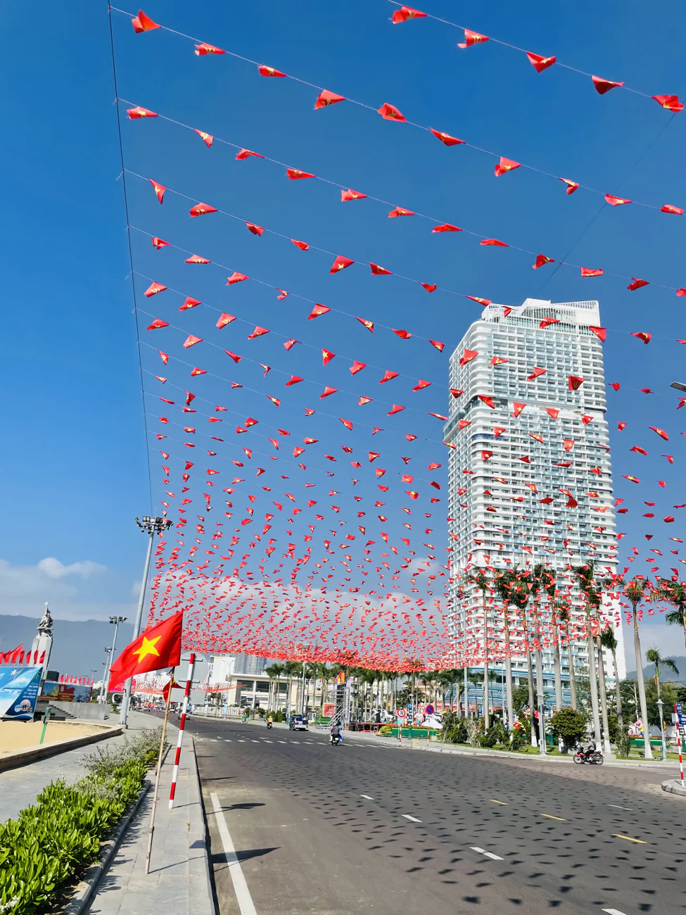 A Quy Nhon street strung with red festival flags under a blue sky