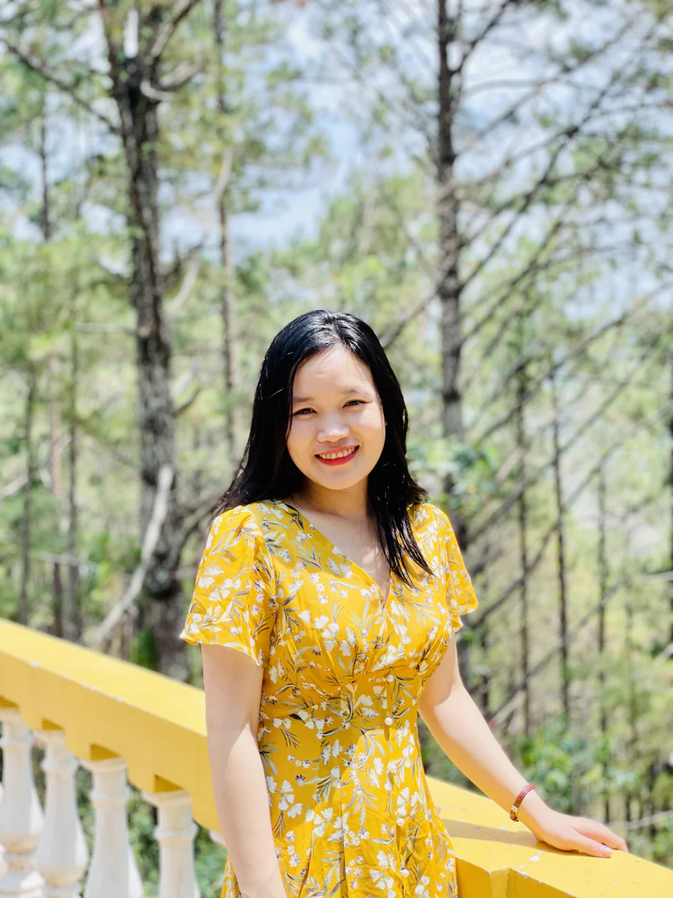 Ly in a yellow dress, smiling in the sunlight